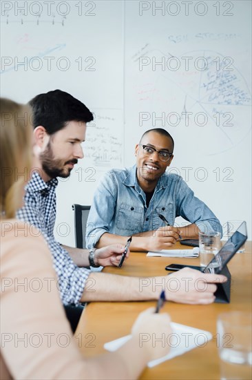 Coworkers using digital tablet in board room