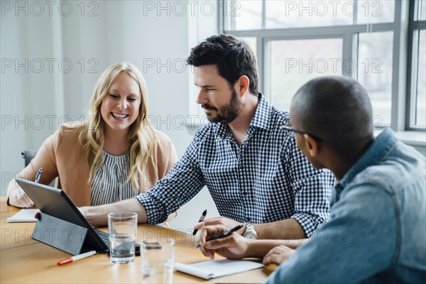 Coworkers using digital tablet in board room