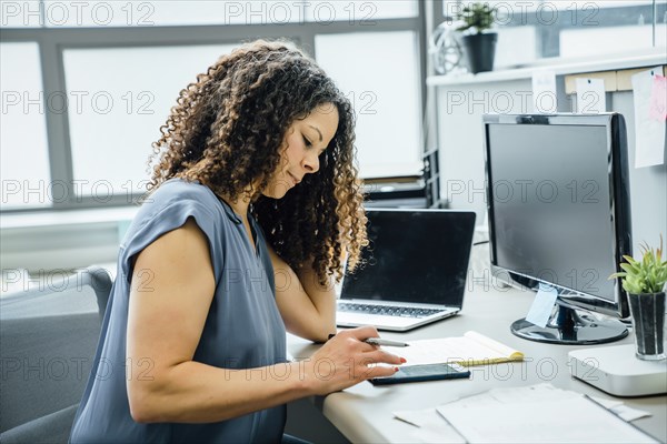 Woman using smart phone in office