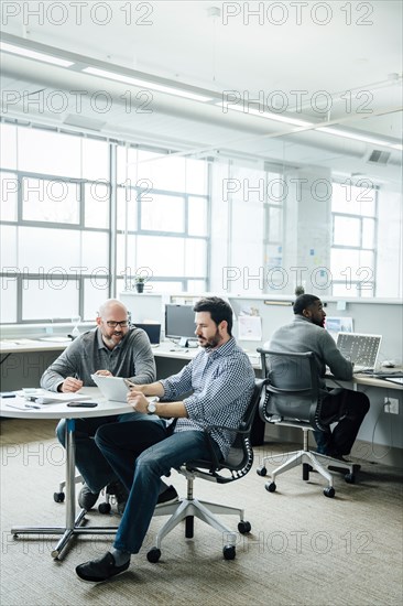 Men using digital tablet during meeting in office