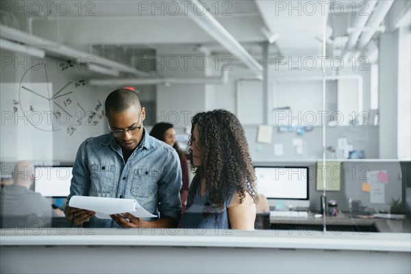 View through window of coworkers reading documents in office