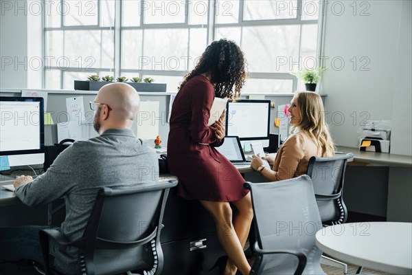 Coworkers talking at desk in office