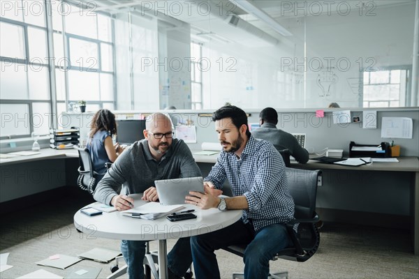 Men using digital tablet during meeting in office