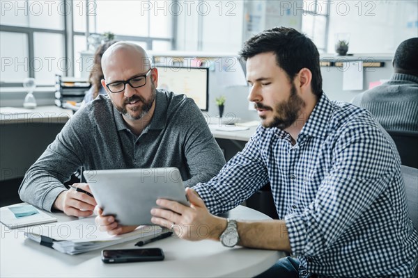 Men using digital tablet during meeting in office