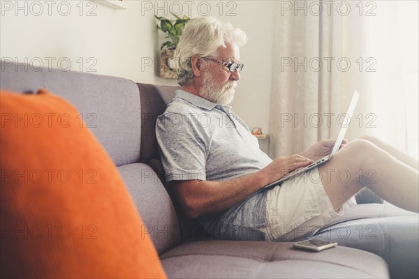 Senior man using laptop on sofa