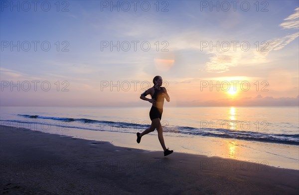 Woman jogging on beach at sunset