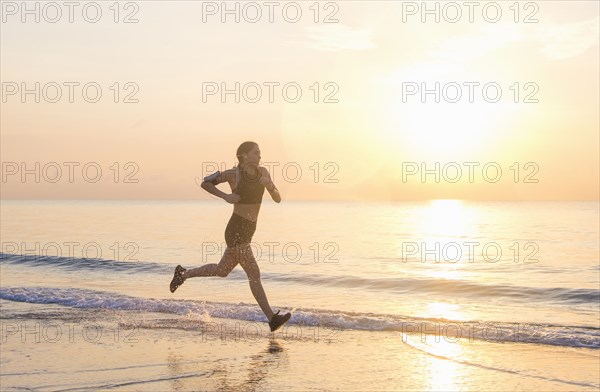 Woman jogging on beach at sunset