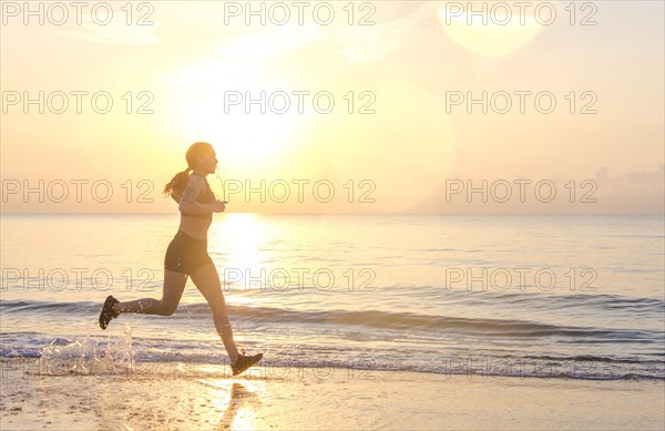 Woman jogging on beach at sunset