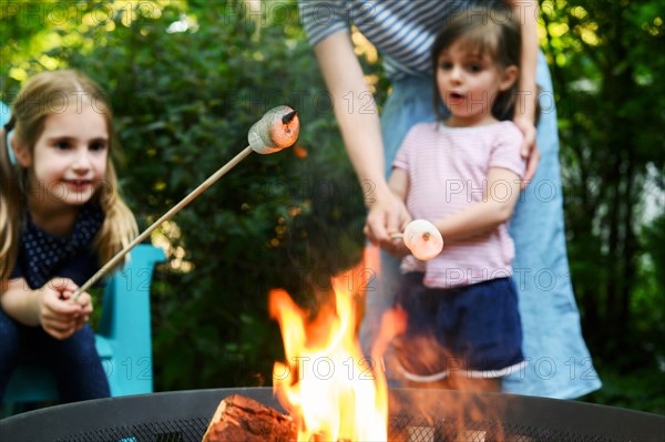 Family toasting marshmallows over brazier