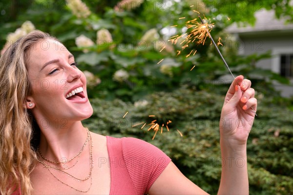 Smiling young woman holding sparkler