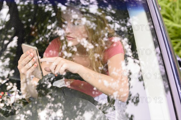 View through car windscreen of young woman using smart phone