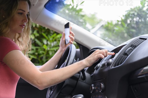 Young woman using smart phone and touchscreen in car