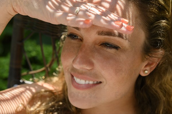 Smiling young woman shielding her eyes