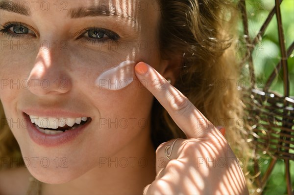 Young woman applying sun cream