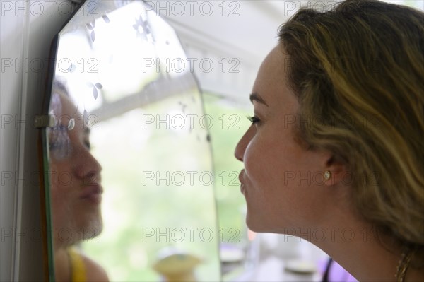 Young woman pouting into mirror