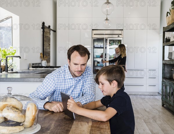 Father and son using digital tablet at dining table