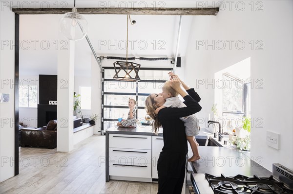 Mother holding son on kitchen counter
