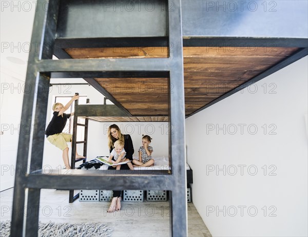 Mother reading story to children on bunk bed