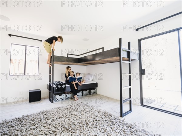 Mother reading story to children on bunk bed