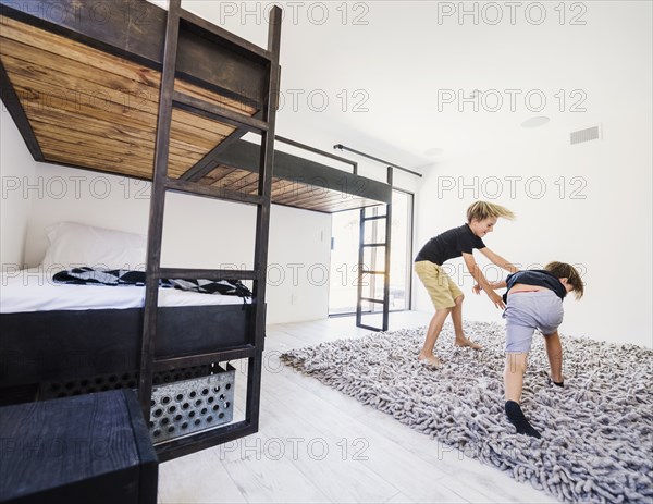 Boys play fighting by bunk beds