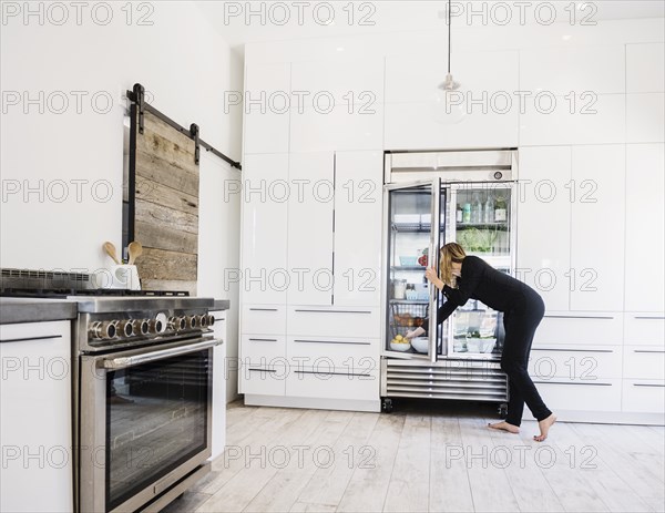 Woman reaching into refrigerator