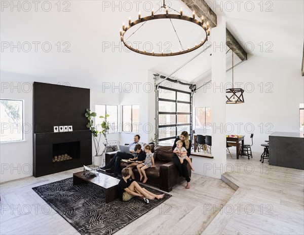 Family with book and laptop on sofa