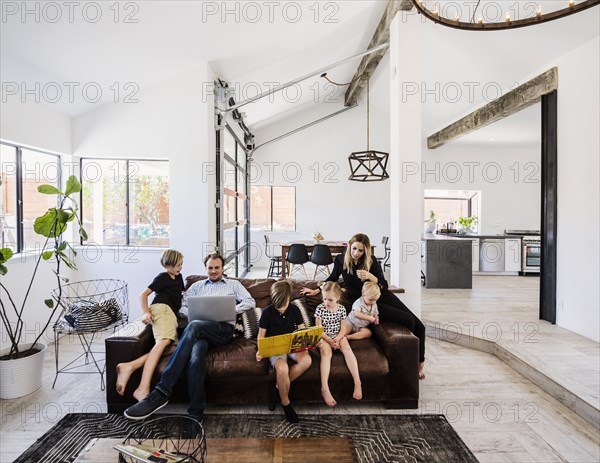 Family with book and laptop on sofa