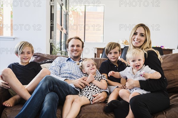 Smiling family sitting on leather sofa