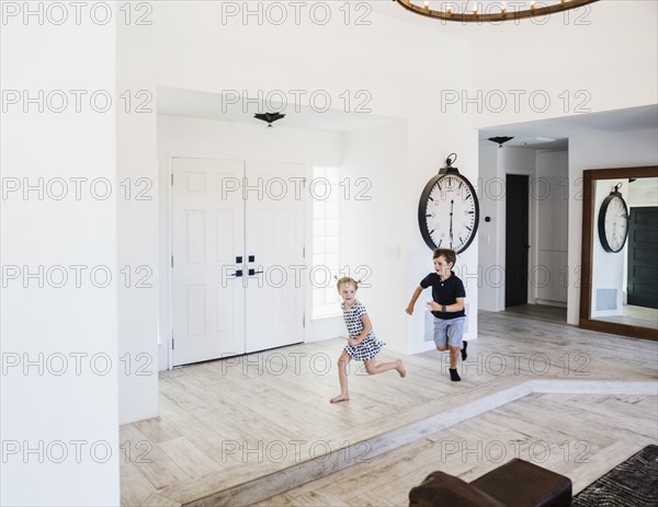 Boy chasing his sister in entrance hall
