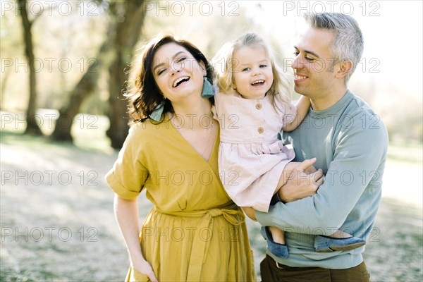 Smiling parents holding their daughter in park