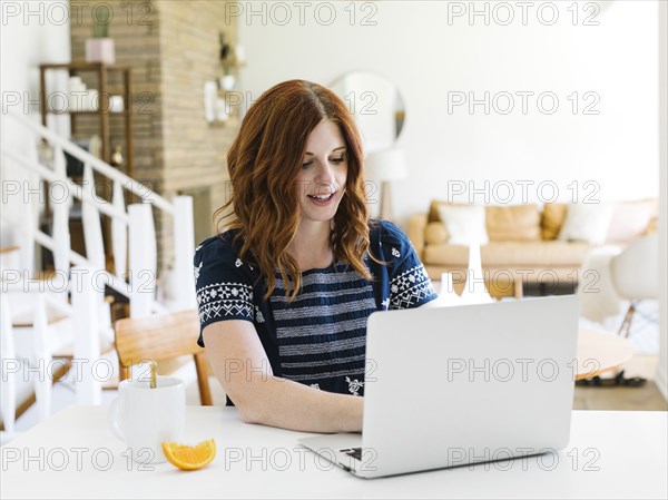 Woman using laptop at dining table