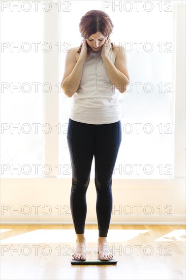 Mid adult woman weighing herself
