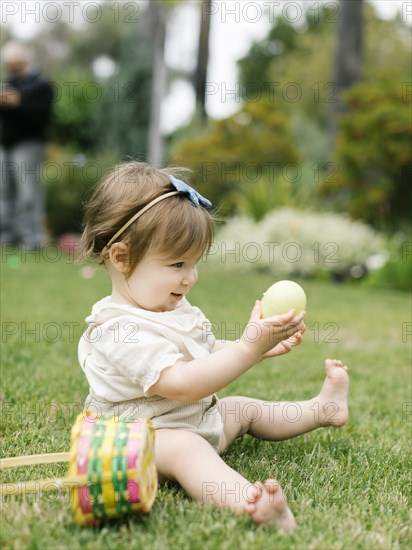 Baby girl with Easter egg and basket in back yard