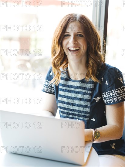 Smiling woman using laptop in cafe