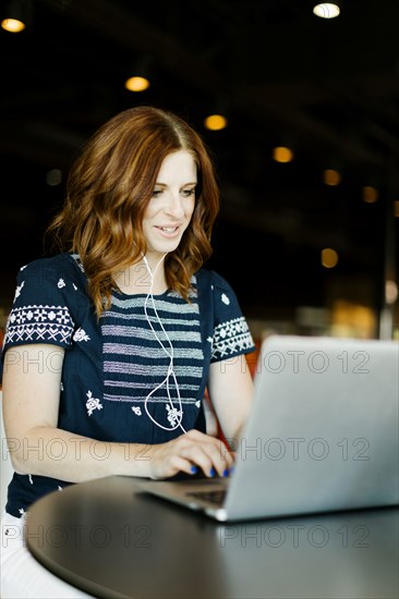 Mid adult woman using laptop and headphones