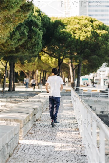 Young man using electric scooter on pavement