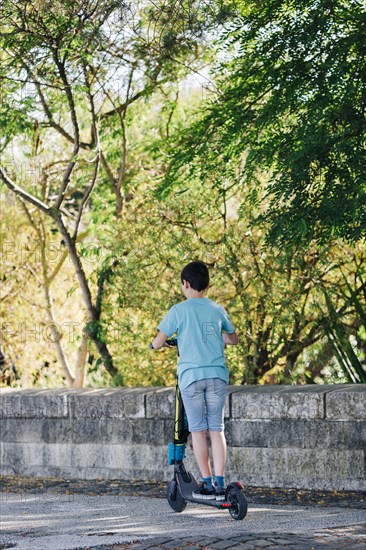 Boy using electric scooter on sidewalk
