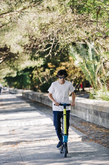 Young man using electric scooter on pavement