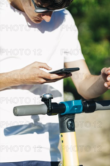 Young man using smart phone on electric scooter
