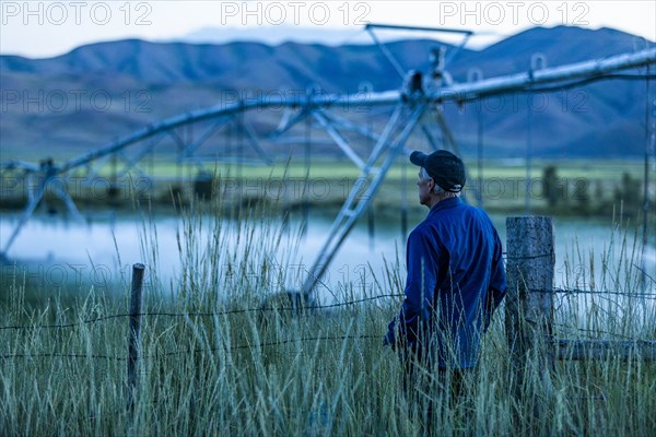 Senior man standing in field by irrigation system