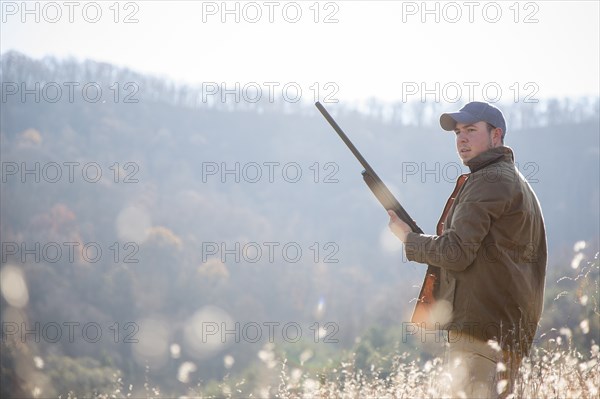 Young man holding rifle in field