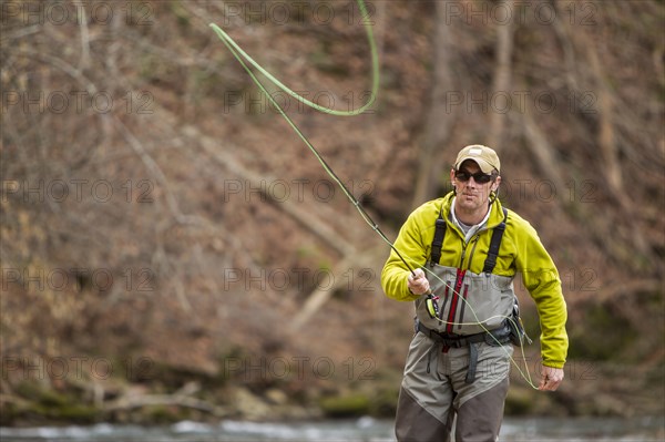 Young man fly-fishing in river