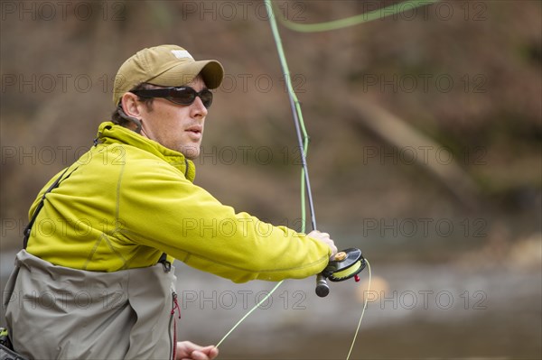 Young man fly-fishing in river