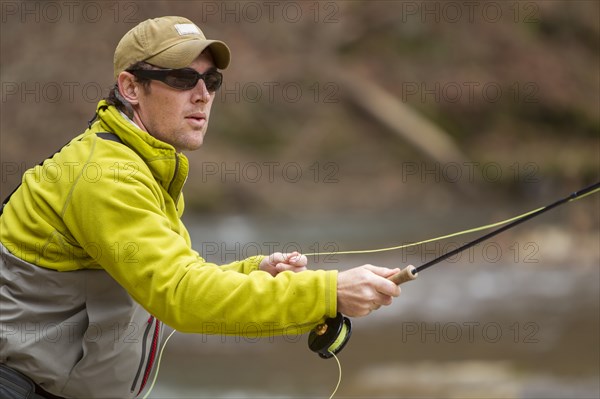 Young man fly-fishing in river