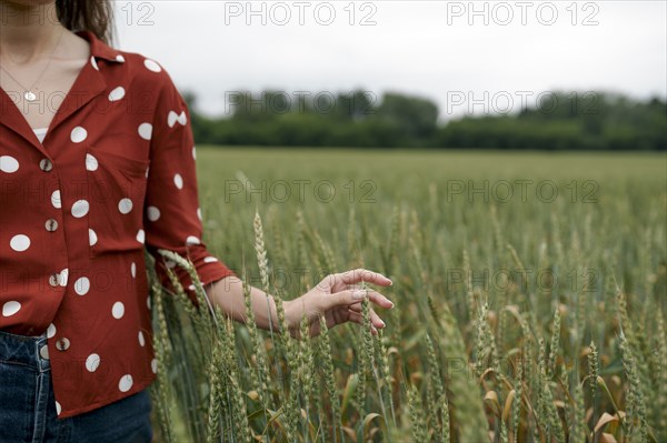 Woman wearing red polka dot shirt in wheat field