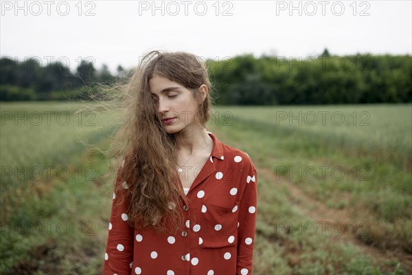 Woman wearing red polka dot shirt in wheat field