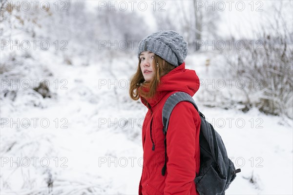 Teenage girl wearing red coat and grey hat in snow