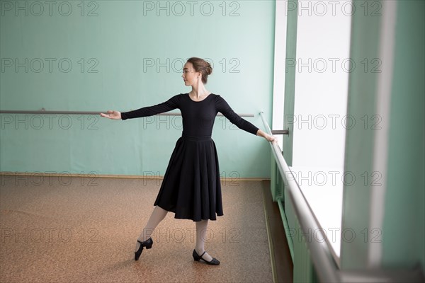 Ballet dancer wearing black dress at barre