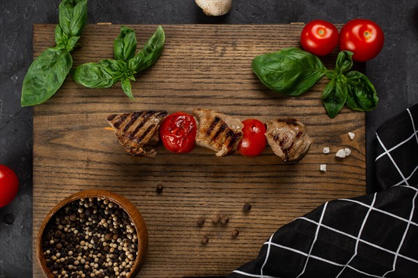 Grilled meat and tomato skewer on cutting board