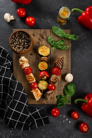 Grilled skewers on cutting board with vegetables